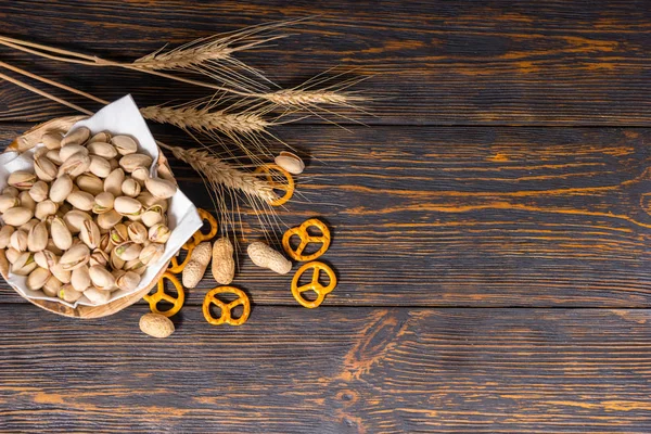 Vista dall'alto del piatto di legno con pistacchi vicino al grano, sparsi s — Foto Stock