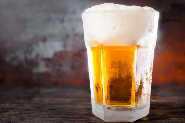 Big glass with a light beer and a large head of foam on old dark — Stock Photo, Image