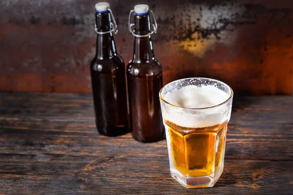 Dos botellas de cerveza cerca del vidrio con una cerveza ligera y una cabeza de espuma —  Fotos de Stock