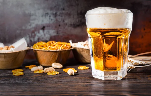 Glass with light beer and a head of foam, plates with pistachios — Stock Photo, Image
