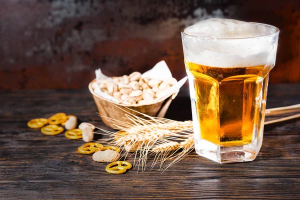 Ποτήρι με την μπύρα και ένα κεφάλι του αφρού κοντά πιάτο με φιστίκια, w — Φωτογραφία Αρχείου