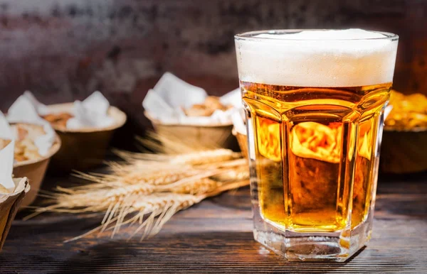 Big glass with freshly poured beer near plates with pistachios, — Stock Photo, Image