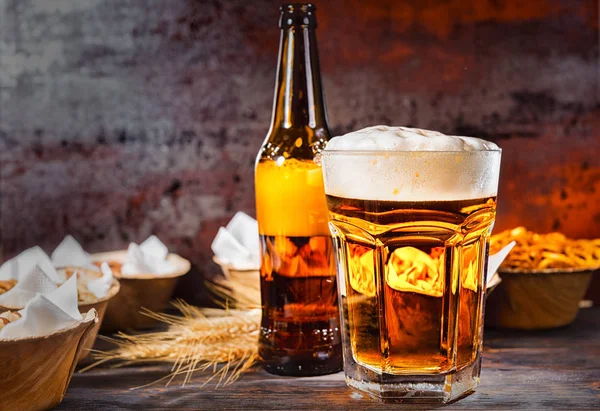 Vidrio con cerveza recién vertida y cabeza de espuma cerca de la botella y — Foto de Stock