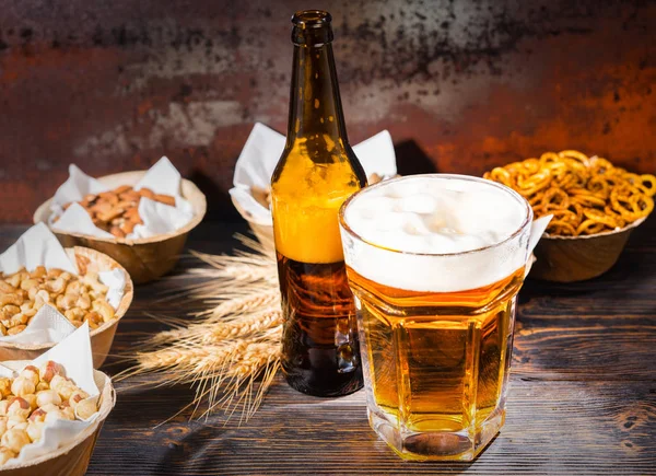 Vidrio con cerveza recién vertida y cabeza de espuma cerca de la botella y — Foto de Stock