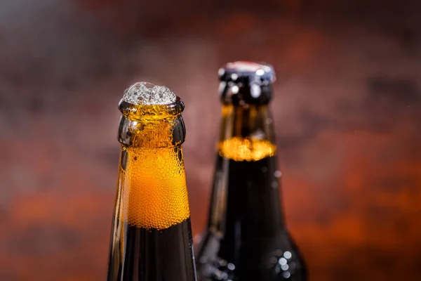 Перелив пива из только что открытой бутылки пива на тёмном фоне — стоковое фото