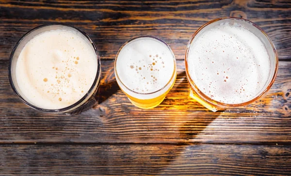 Top view of three glasses with light, unfiltered and dark beer o — Stock Photo, Image