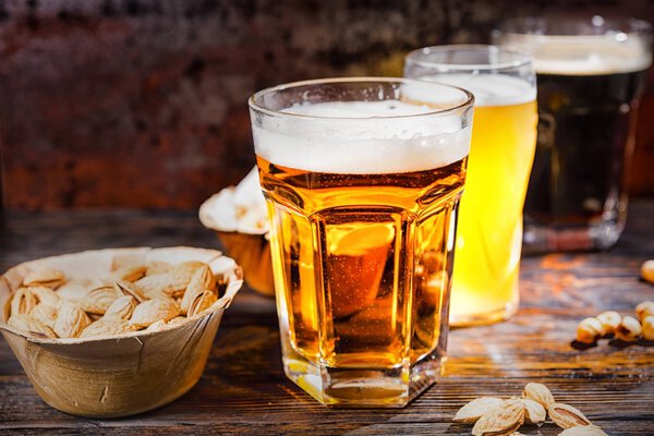 Три стакана с легким, нефильтрованным и темным пивом стоят в ро
