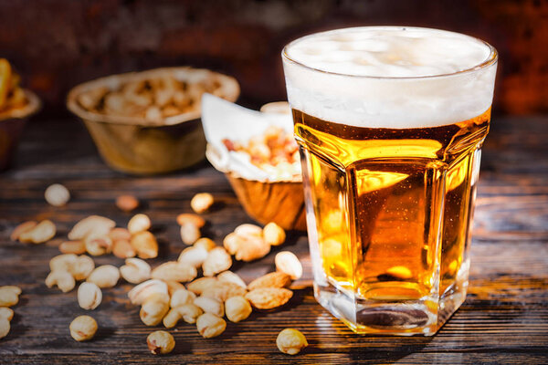 Стекло со свежим светлым пивом рядом с тарелками с закусками и
