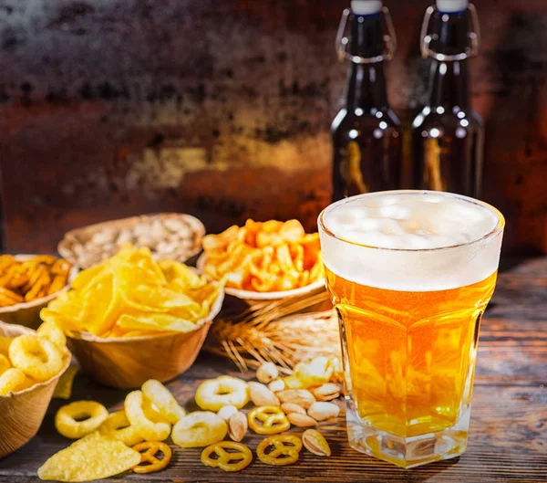 Platos con bocadillos cerca de dos botellas y un vaso de cerveza, trigo , — Foto de Stock