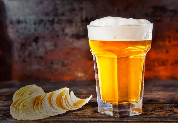 Velké sklenice čerstvě položeného světlé pivo poblíž chips na tmavý dřevěný — Stock fotografie