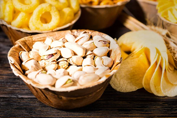 Close up of wooden plate with pistachios near wooden plates with — Stock Photo, Image