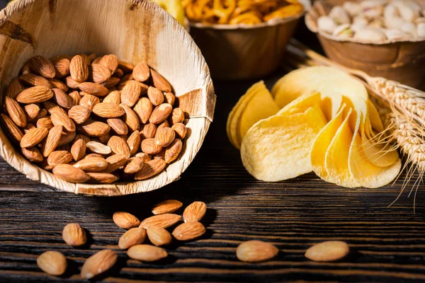 Close up of wooden plate with almonds near wooden plates with sn — Stock Photo, Image