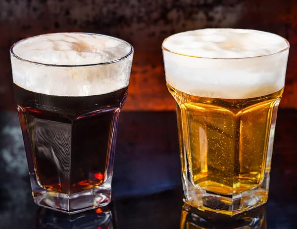 Два стакана со свежим темным и светлым пивом на черный м — стоковое фото