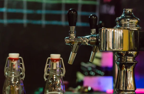 Torneiras de cerveja em fila no restaurante ou pub perto de garrafas de cerveja vazias — Fotografia de Stock