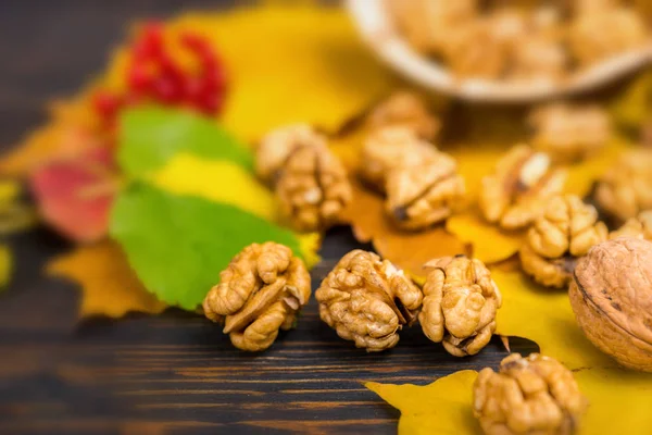 Close up of slightly scattered walnuts lying on leaves on wooden — Stock Photo, Image