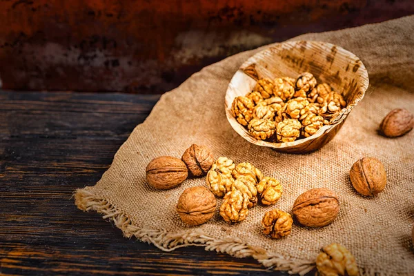 Slightly scattered walnuts lying on linen cloth near wooden plat — Stock Photo, Image