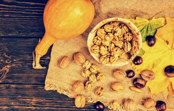 Vista superior de la placa de madera con nueces en tela de lino cerca de calabazas —  Fotos de Stock