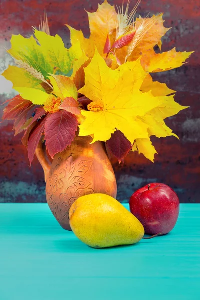 Pot d'argile avec feuilles d'automne et blé près d'une pomme et d'une poire o — Photo