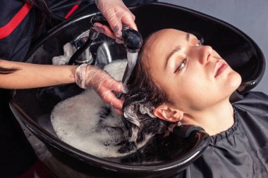 High angle view of young woman having hair washed by stylist aft clipart