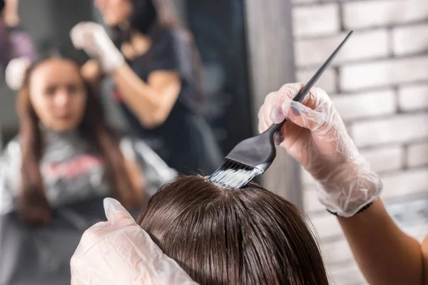 Крупный план женских рук парикмахера окрашивает волосы клиента — стоковое фото