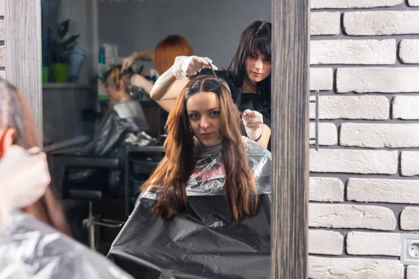 Приваблива жінка-перукар тримає в руці замок брюнетки волосатий — стокове фото