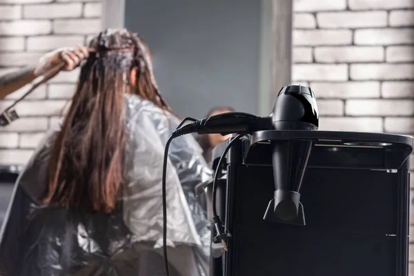 Fokus auf Haartrockner auf einem speziellen Stand in der Nähe weiblicher Stylisten Farbstoff — Stockfoto