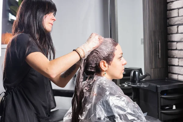 Unga stylist står och gnuggar resten av färgen i håret — Stockfoto