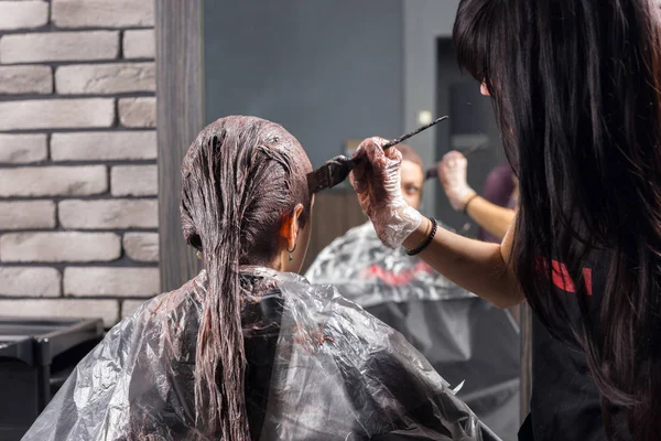 Joven estilista se para y termina el proceso de teñir el cabello de youn — Foto de Stock