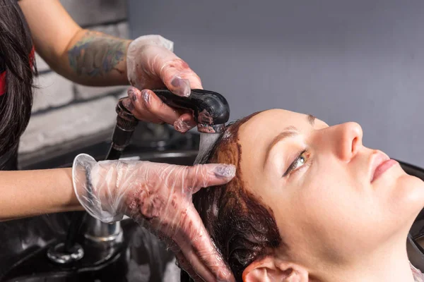 Close up of hairdresser hands washing hair of female client with — Stock Photo, Image