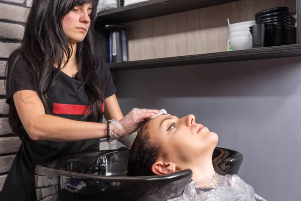 Женщина-парикмахер вытирает остатки краски хлопком — стоковое фото