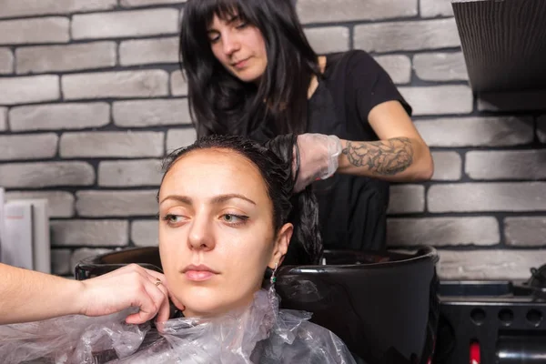 Dwa stylistów wezme kitel kobiety po umyciu włosy w — Zdjęcie stockowe
