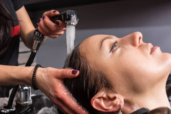 Close-up van handen van vrouwelijke stylist wast uit de shampoo van jongeren — Stockfoto