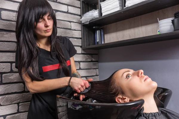 Estilista profesional femenina peinando el cabello de mujeres jóvenes hermosas — Foto de Stock