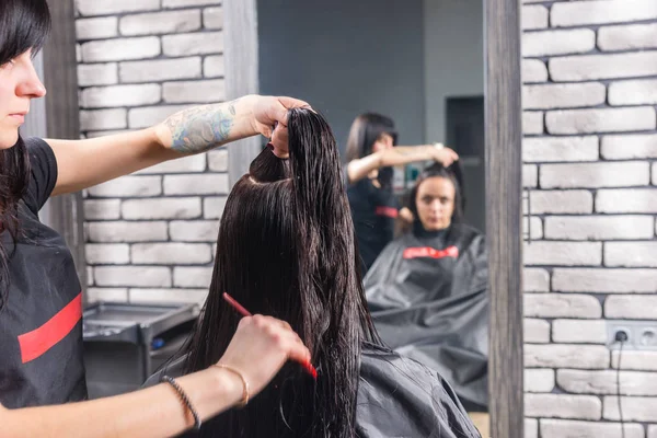 Cabeleireiro feminino faz uma separação e penteia o cabelo molhado de brunett — Fotografia de Stock