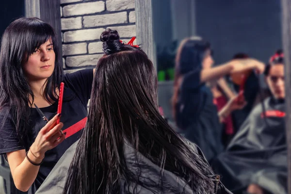 Профессиональный парикмахер расчесывает и стрижет мокрые волосы молодых б — стоковое фото