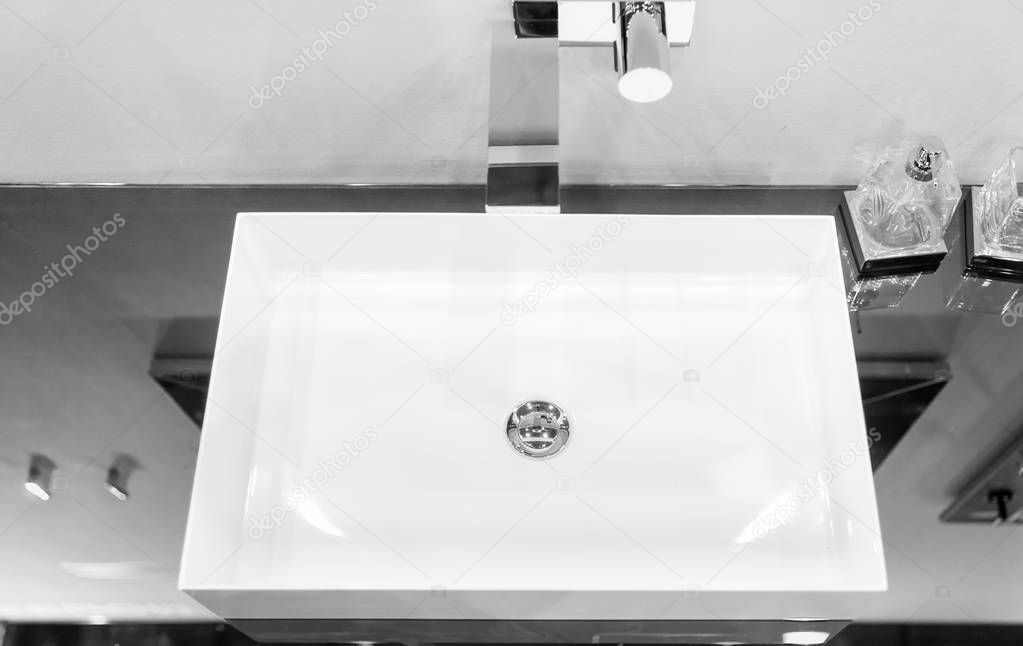Modern square washbasin mounted in a mirror surface near glass c