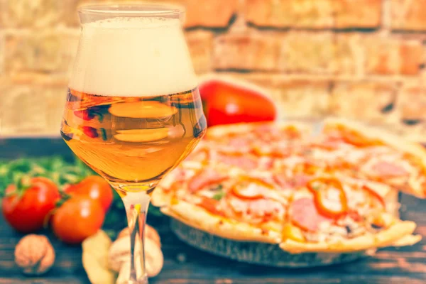 Склянка пива та піци з салямі на фоні — стокове фото