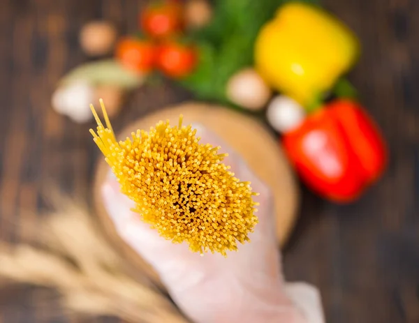 Close up of bunch of yellow long spaghetti above wooden stand — Stock Photo, Image
