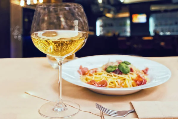 Закрыть бокал с вином рядом с вкусной спагетти-пастой во время отдыха — стоковое фото