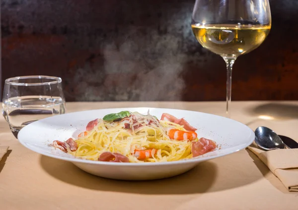 Cam şarap yakınındaki karides, spagetti makarna ile rendelenmiş peynir
