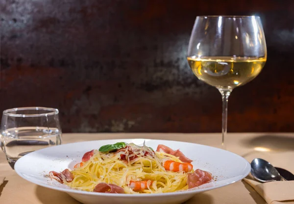 Glass with wine near tasty spaghetti pasta with shrimps, grated — Stock Photo, Image