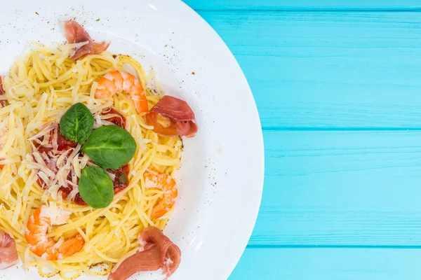 Close up of appetizing spaghetti pasta in white plate on blue wo — Stock Photo, Image