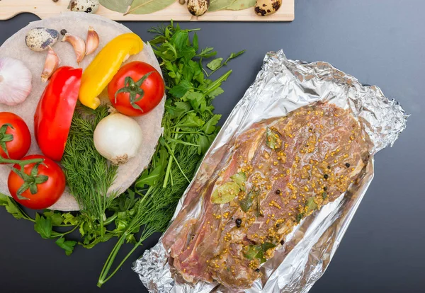 High angle view of marinated meat on foil near vegetables on a g — Stock Photo, Image