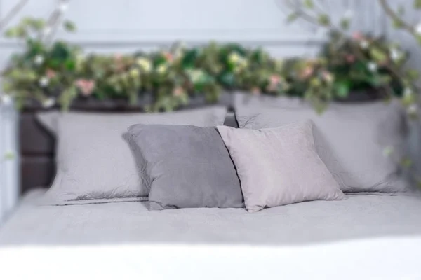 Céntrate en las almohadas grises, cama acogedora con flores en la cama y —  Fotos de Stock