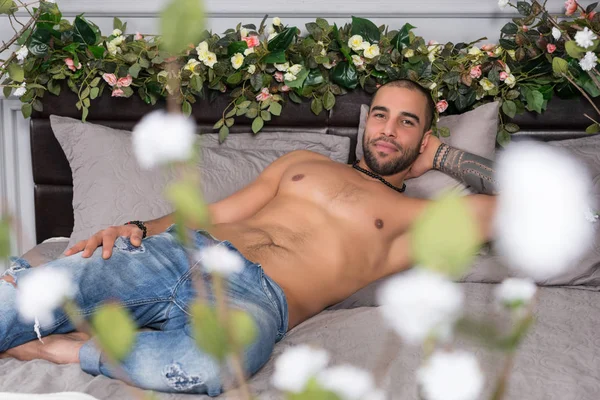 Knappe moslim man glimlachend met blote borst liggend op de grijze co — Stockfoto
