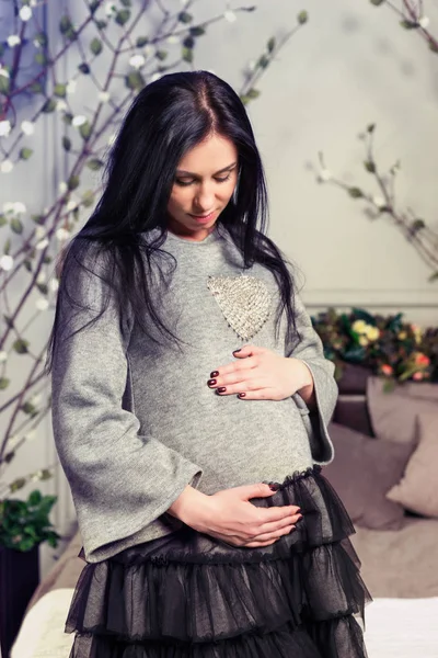 Mulher morena grávida atraente mantendo as mãos na barriga standi — Fotografia de Stock