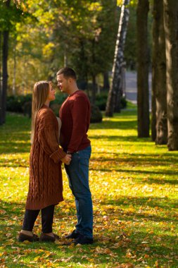 Birbirine aşık iki genç el ele durur.