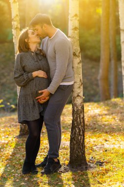 Parlayan güneşte şefkatle öpüşen sevgili çift