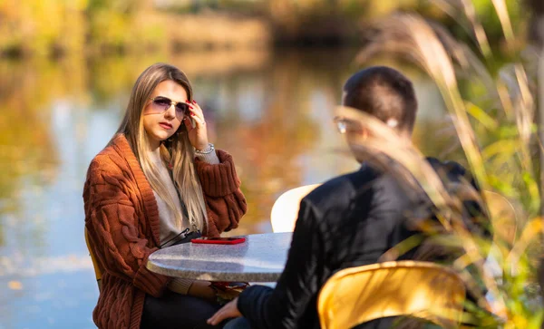 Attraktive junge Frau sitzt an einem Tisch im Freien — Stockfoto