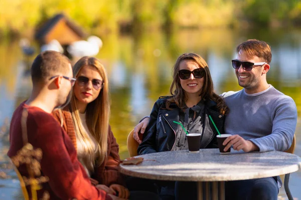 Two young couples enjoying drinks outdoors — Stock Photo, Image